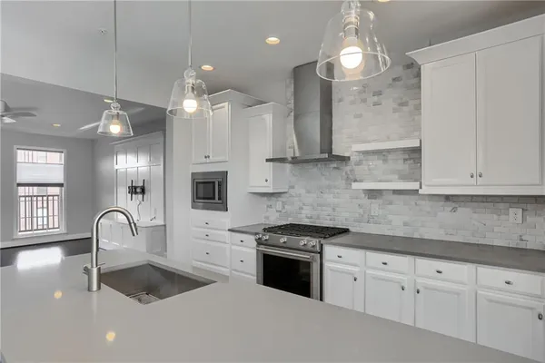 a kitchen with granite countertop a stove a sink a refrigerator and a white cabinets
