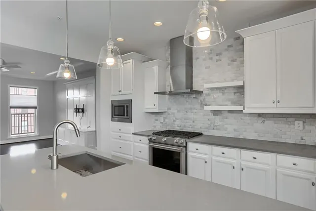 a kitchen with granite countertop a stove a sink a refrigerator and a white cabinets