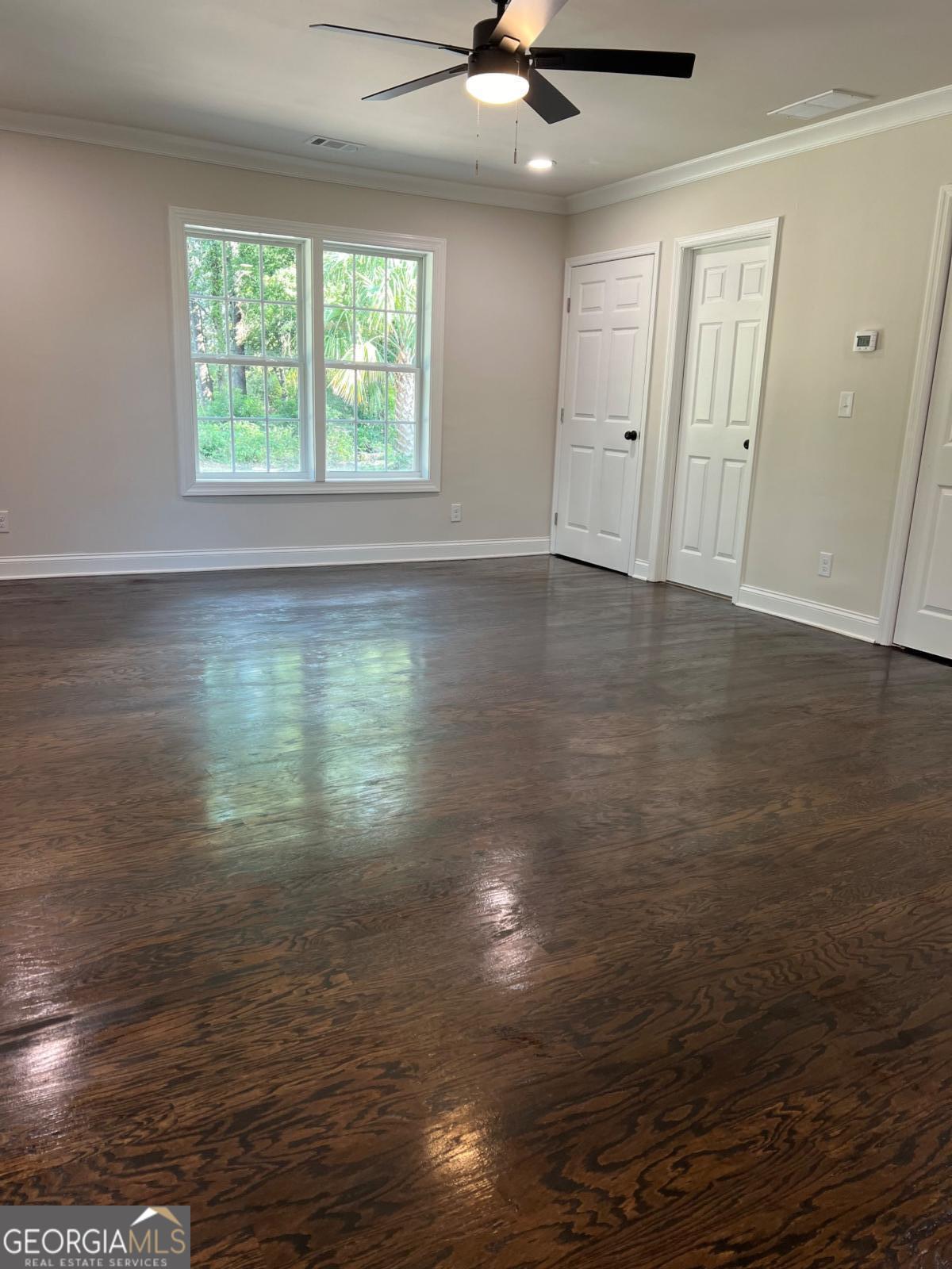 213 Fair Street Baxley, GA 31513 - Photo 12 of 29 an empty room with wooden floor fan and windows