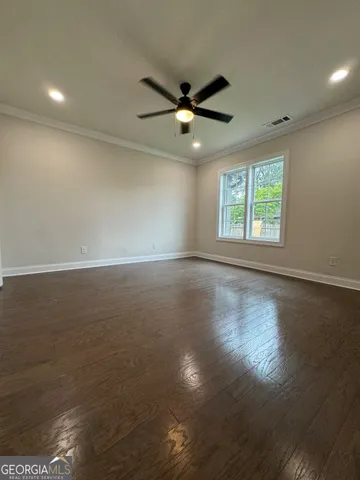 an empty room with wooden floor fan and windows