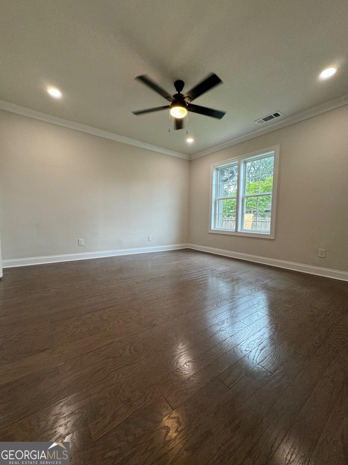 213 Fair Street Baxley, GA 31513 - Photo 24 of 29 an empty room with wooden floor fan and windows