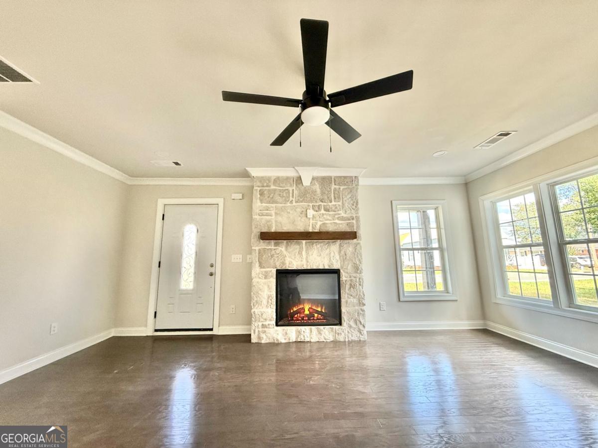 213 Fair Street Baxley, GA 31513 - Photo 6 of 29 an empty room with fireplace wooden floor and windows