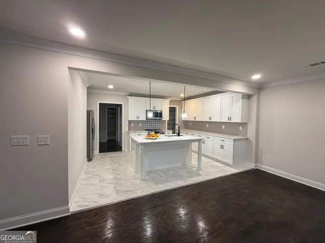 a large white kitchen with a refrigerator a sink dishwasher and a stove with wooden floor