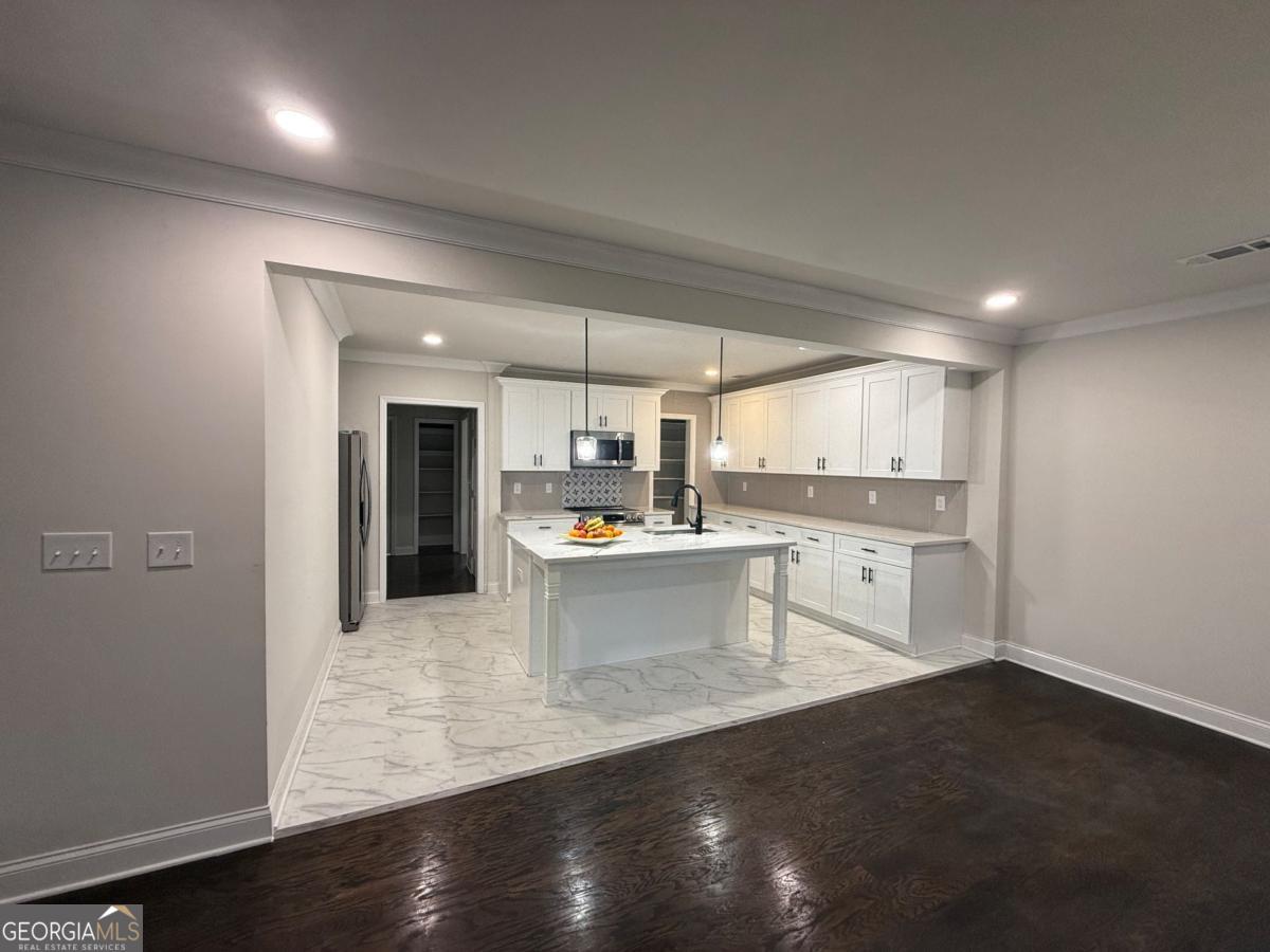 213 Fair Street Baxley, GA 31513 - Photo 10 of 29 a large white kitchen with a refrigerator a sink dishwasher and a stove with wooden floor