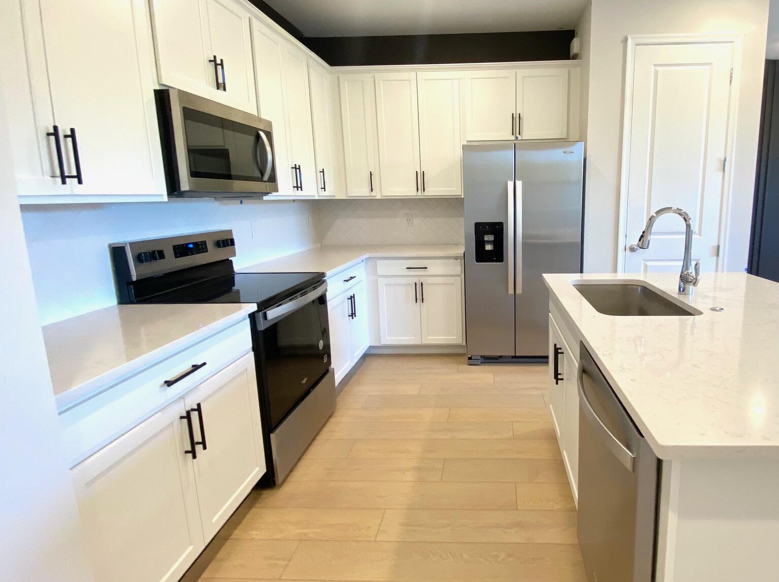 276 Southwest Sally Way, Unit LATITUDE 6613 Stuart, FL 34997 - Photo 5 of 22 a kitchen with stainless steel appliances granite countertop a refrigerator a stove top oven a sink and dishwasher