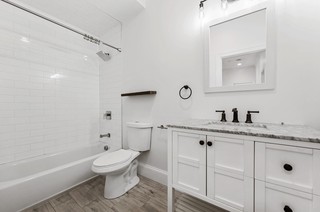 6 Marie Street, Unit 3 Boston, MA 02122 - Photo 18 of 25 a bathroom with a granite countertop toilet sink and mirror