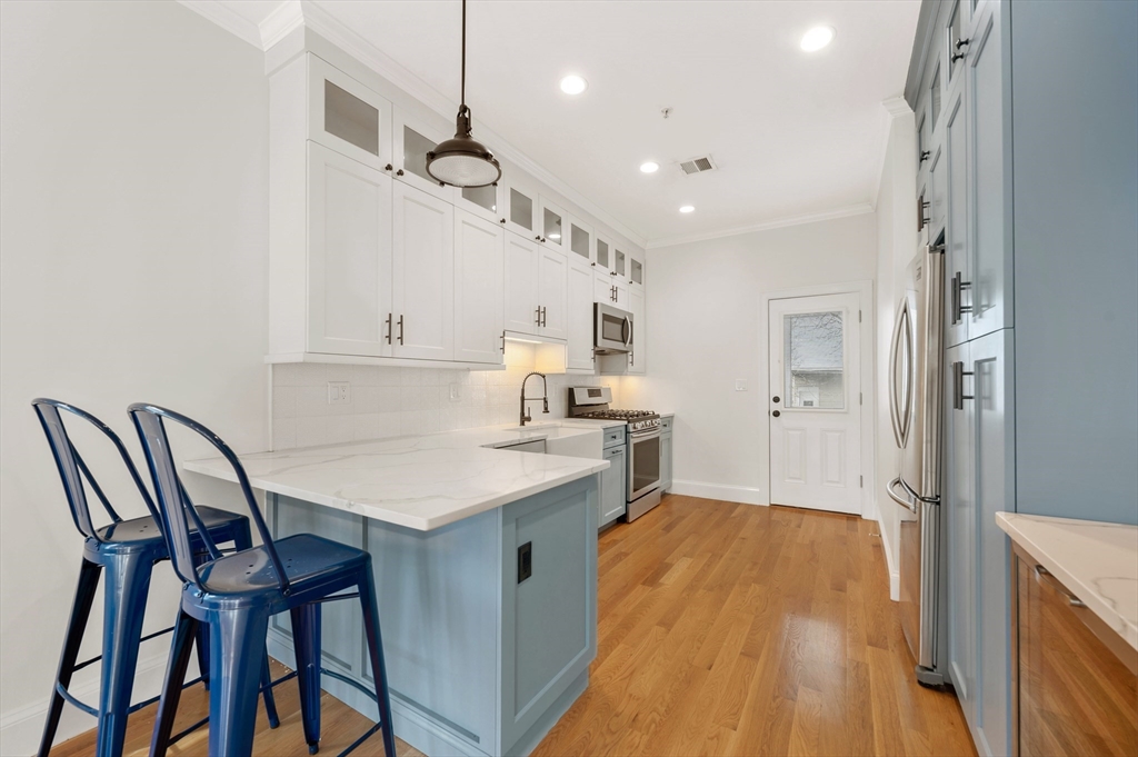 6 Marie Street, Unit 3 Boston, MA 02122 - Photo 3 of 25 a kitchen with a table chairs refrigerator and cabinets