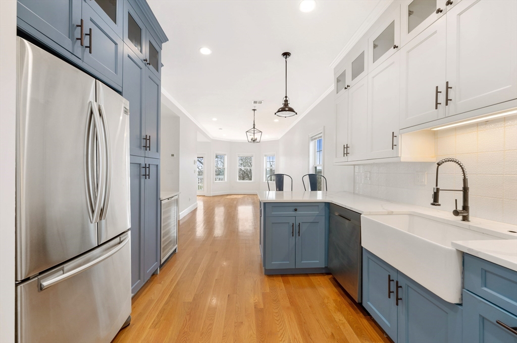 6 Marie Street, Unit 3 Boston, MA 02122 - Photo 6 of 25 a kitchen with stainless steel appliances a refrigerator a sink dishwasher a stove and white cabinets with wooden floor