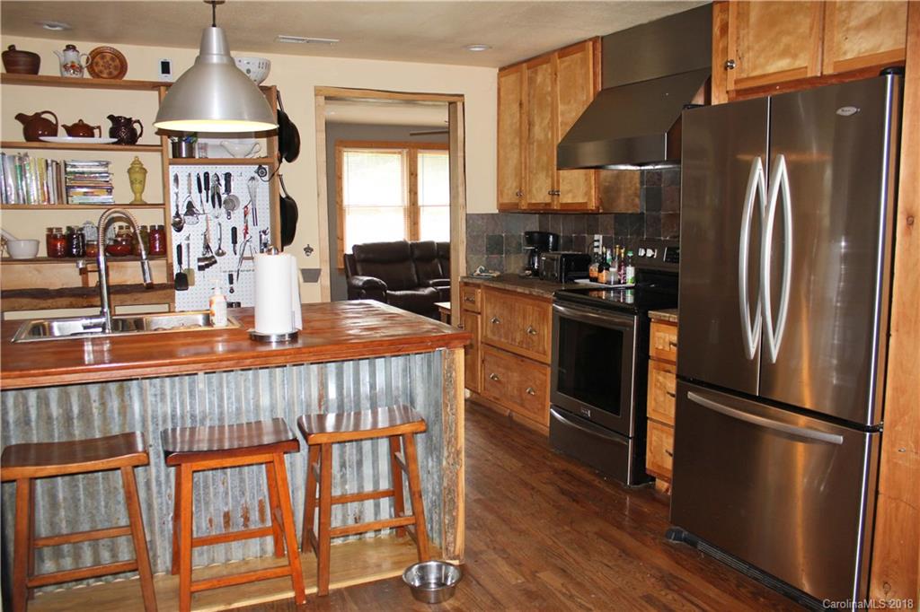 214 Huffman Road Clyde, NC 28721 - Photo 7 of 24 a kitchen with stainless steel appliances granite countertop a refrigerator a stove a sink and a dining table with wooden floor