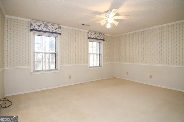 an empty room with windows and fan