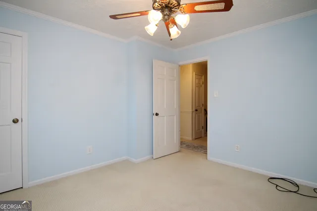 an empty room with a chandelier fan and wooden floor