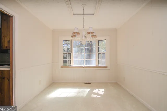 an empty room with chandelier fan and windows