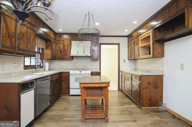a kitchen with stainless steel appliances granite countertop a sink a stove cabinets counter space and wooden floor