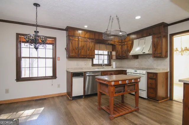 a kitchen with stainless steel appliances granite countertop wooden floors stove and cabinets