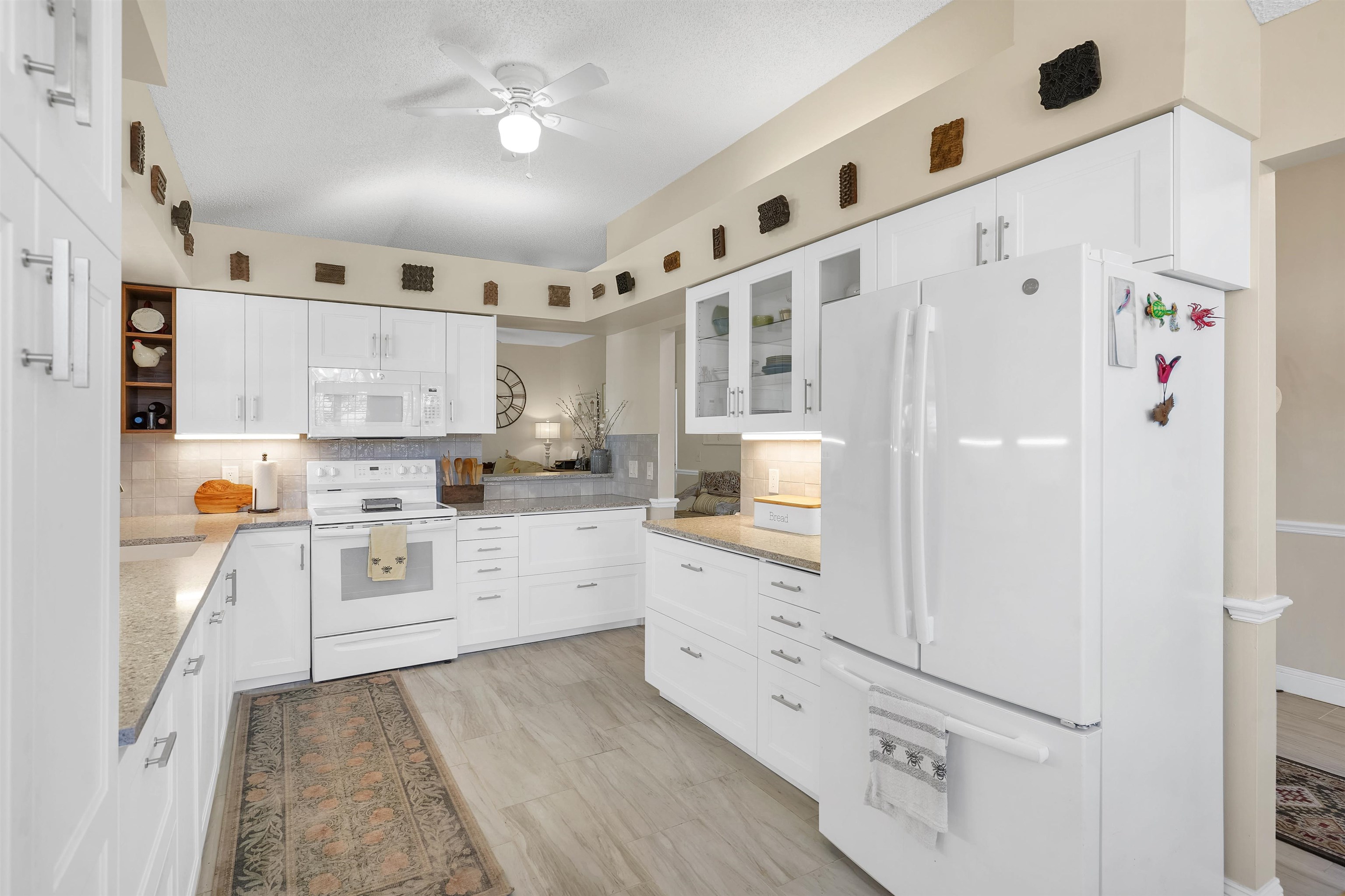 321 Mystical Way St. Augustine, FL 32080 - Photo 5 of 46 Kitchen with white appliances, white cabinetry, glass insert cabinets, and light stone counters