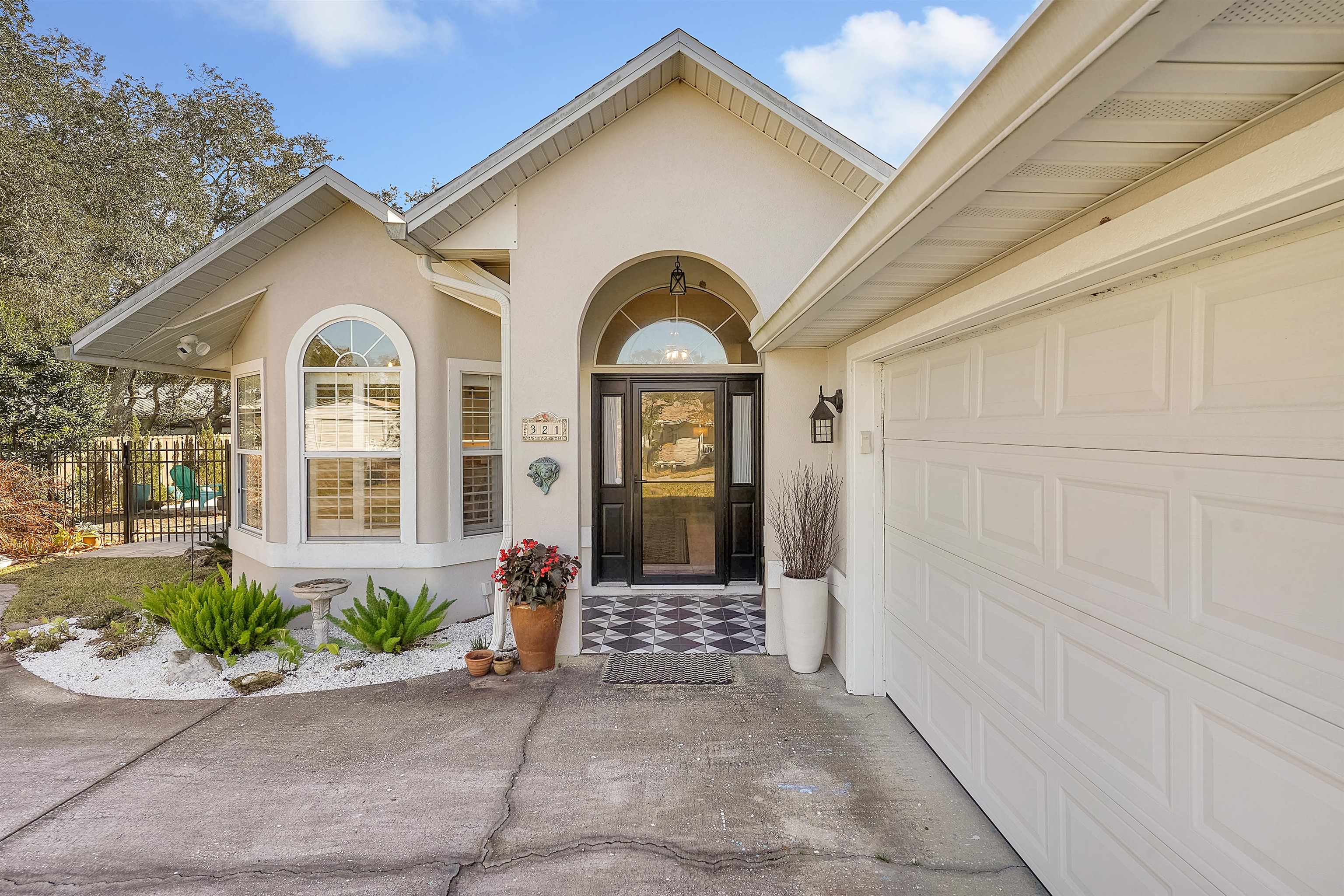 321 Mystical Way St. Augustine, FL 32080 - Photo 7 of 46 View of exterior entry featuring stucco siding, concrete driveway, and a garage