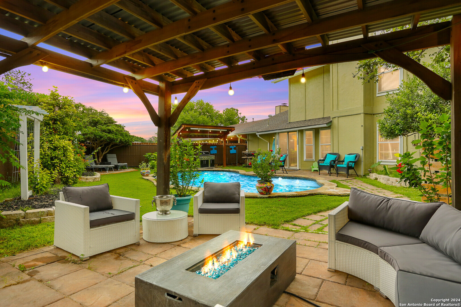 a view of a patio with couches potted plants and a large tree