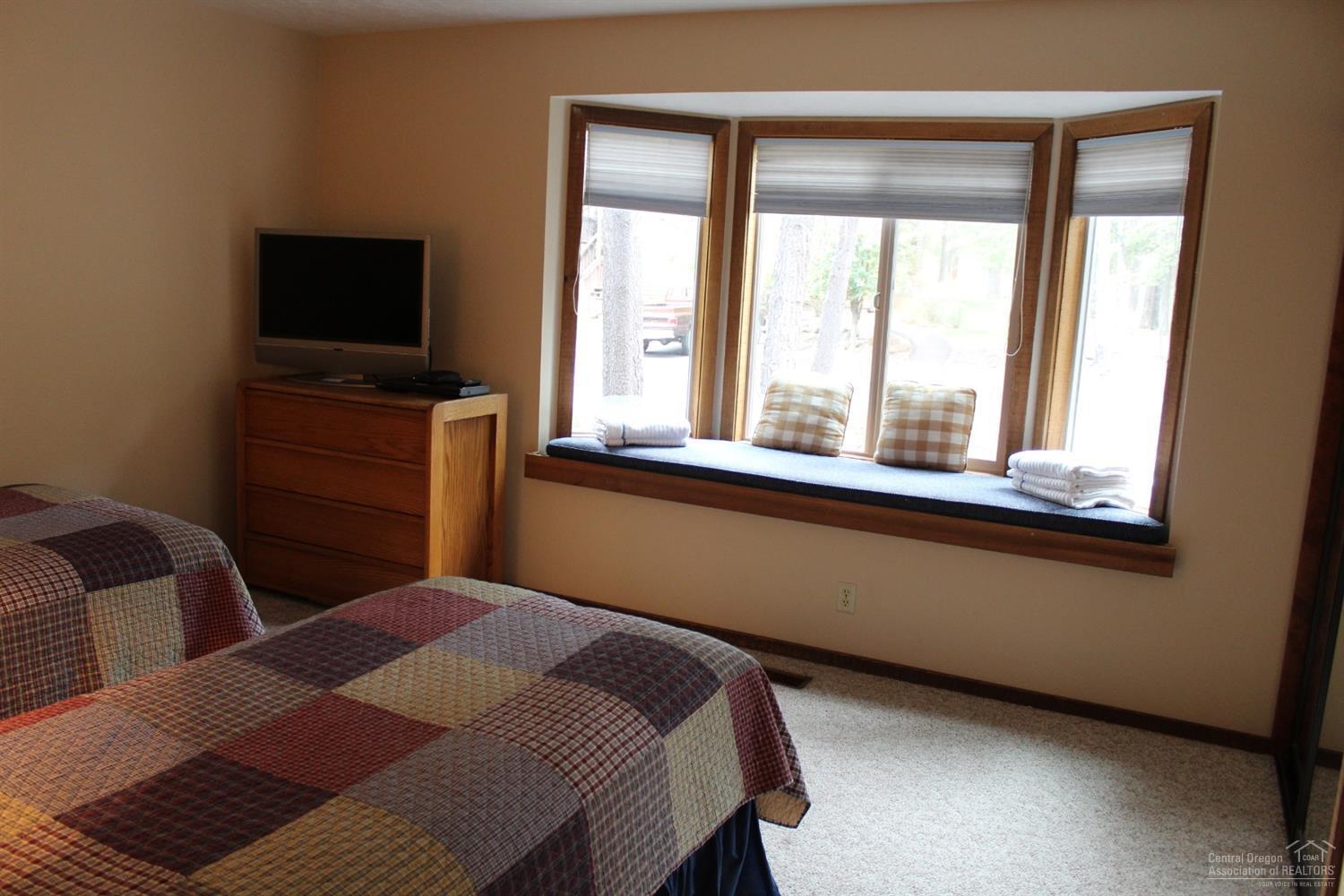 57328 Beaver Ridge Loop Sunriver, OR 97707 - Photo 10 of 22 a bedroom with a bed and a flat tv screen on a dresser