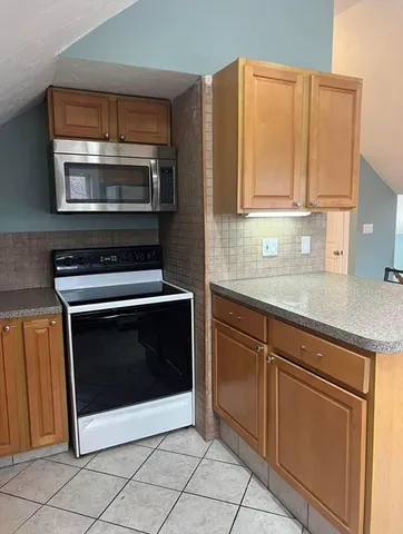 a kitchen with granite countertop a stove top oven microwave and cabinets