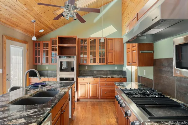 a kitchen with stainless steel appliances kitchen island granite countertop a stove and a sink