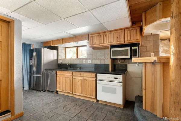 a kitchen with stainless steel appliances granite countertop a refrigerator a stove and a sink with dishwasher