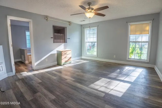 an empty room with wooden floor and windows
