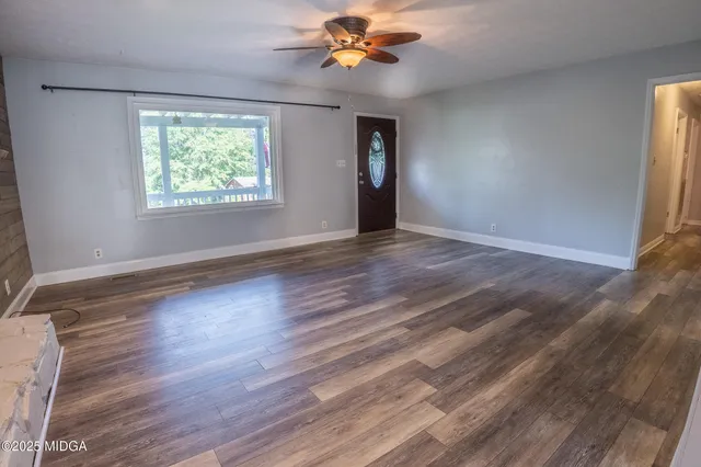 a view of an empty room with window and wooden floor