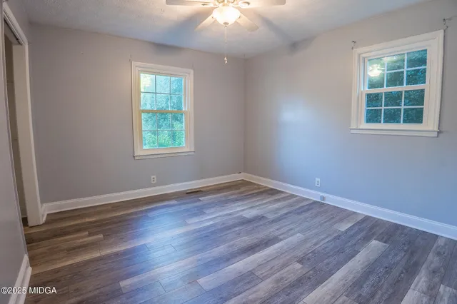 an empty room with wooden floor and windows