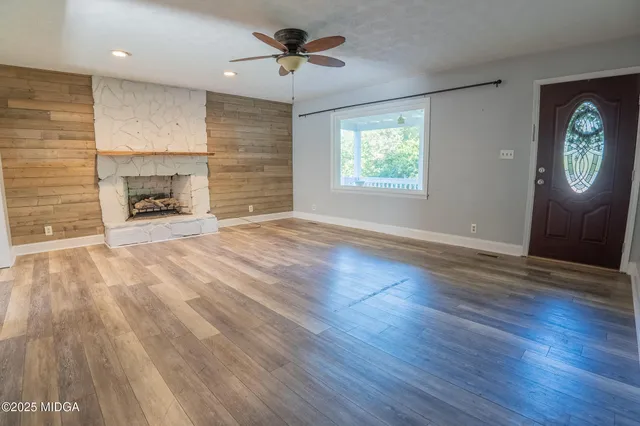 an empty room with windows fireplace and wooden floor