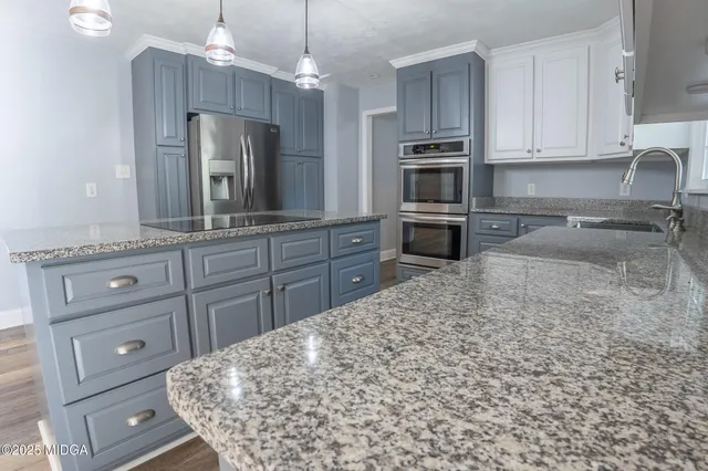 a kitchen with granite countertop a oven a stove and a sink with cabinets