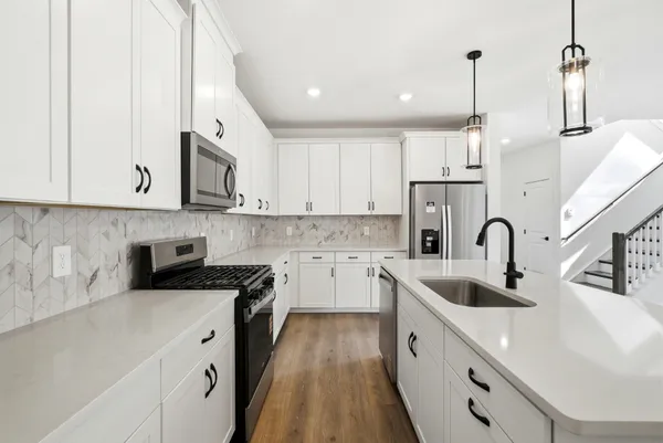 a kitchen with stainless steel appliances granite countertop a sink a stove and a wooden floors