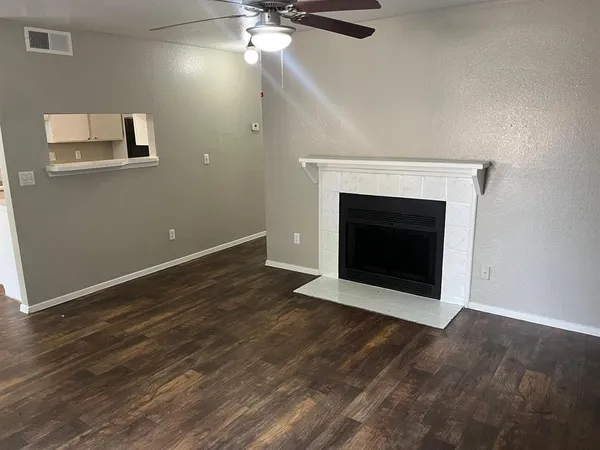 a view of an empty room with wooden floor and a fireplace