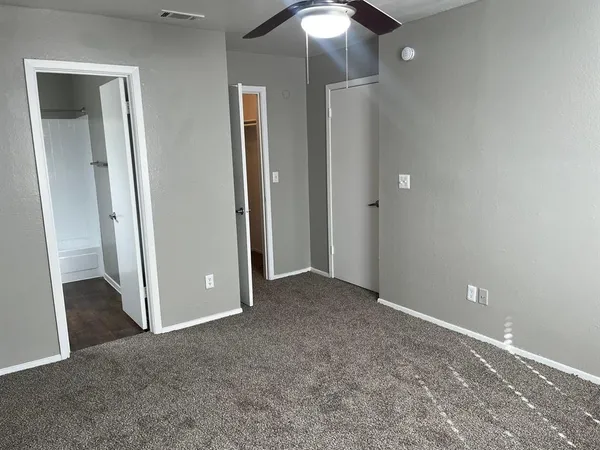 an empty room with closet and a chandelier fan