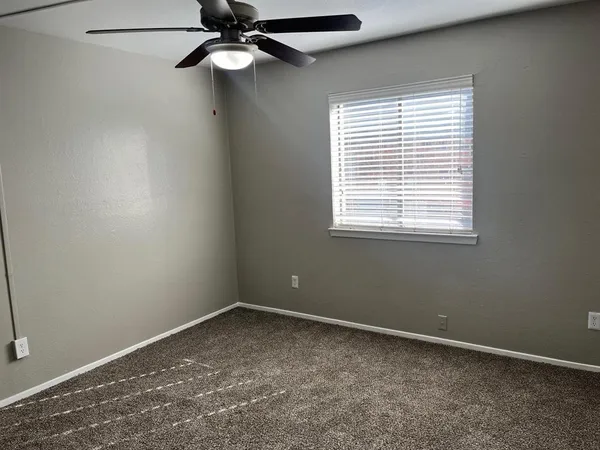 an empty room with a window and a fan