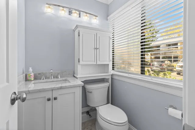 a bathroom with a granite countertop toilet a sink a mirror and a window