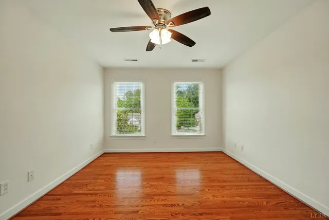 an empty room with a window and a ceiling fan