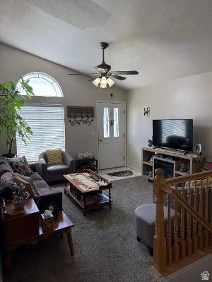 641 East Greystone Way Tooele, UT 84074 - Photo 4 of 30 Vaulted ceiling living area featuring a decorative arched window, a ceiling fan with integrated lighting, a front entry door with glass inserts, and wood baluster staircase