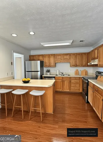 a kitchen with stainless steel appliances granite countertop a stove top oven a sink dishwasher and white cabinets with wooden floor
