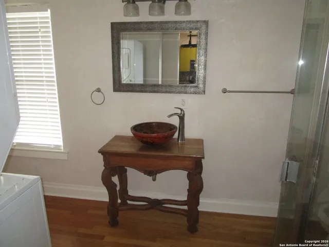 a bathroom with a sink a mirror and wooden floor