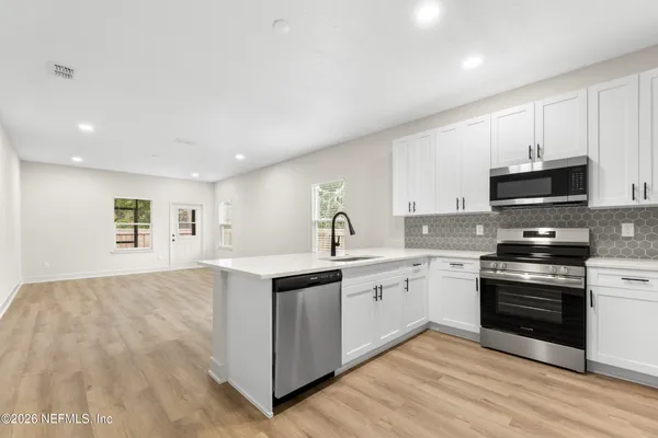 a kitchen with stainless steel appliances a sink a stove a microwave and cabinets
