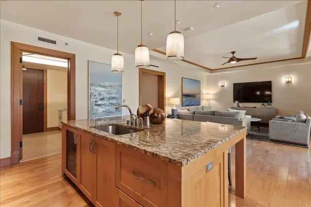 a kitchen with granite countertop a sink a counter top space and living room view