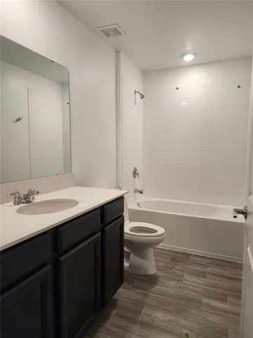 a bathroom with a bathtub shower sink vanity mirror and toilet