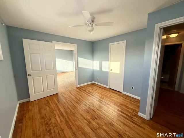 a view of empty room with wooden floor and fan