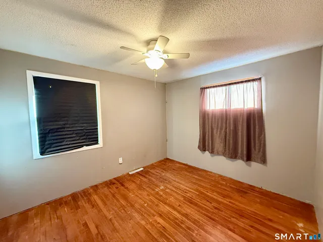 a view of an empty room with window and chandelier fan