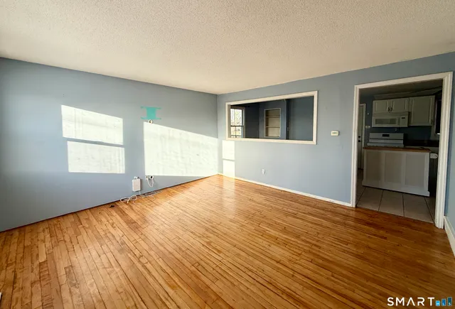 a view of an empty room with a window and wooden floor