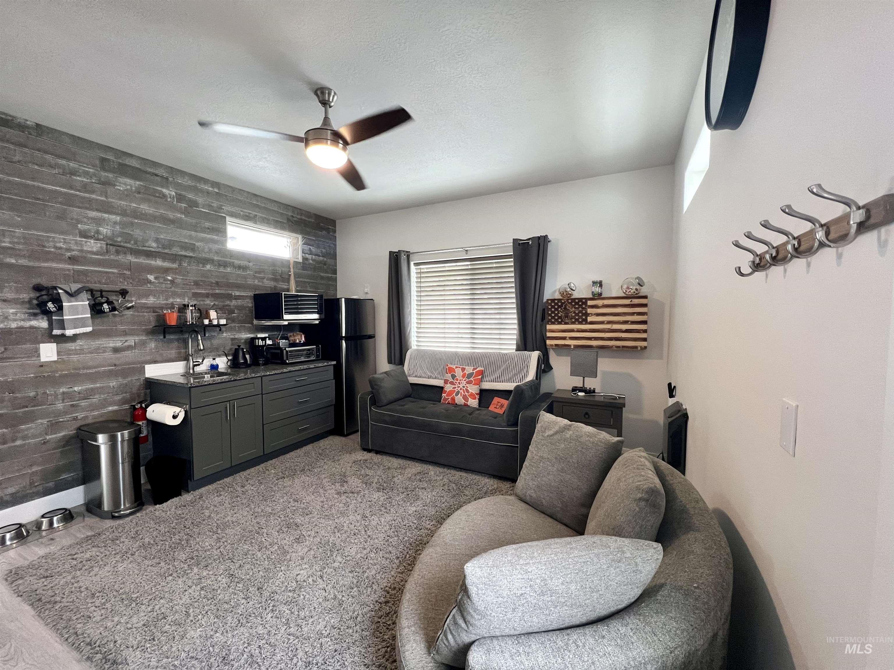 1085 Easy Avenue Twin Falls, ID 83301 - Photo 16 of 22 Living room with wood walls, a textured ceiling, an accent wall, and a ceiling fan