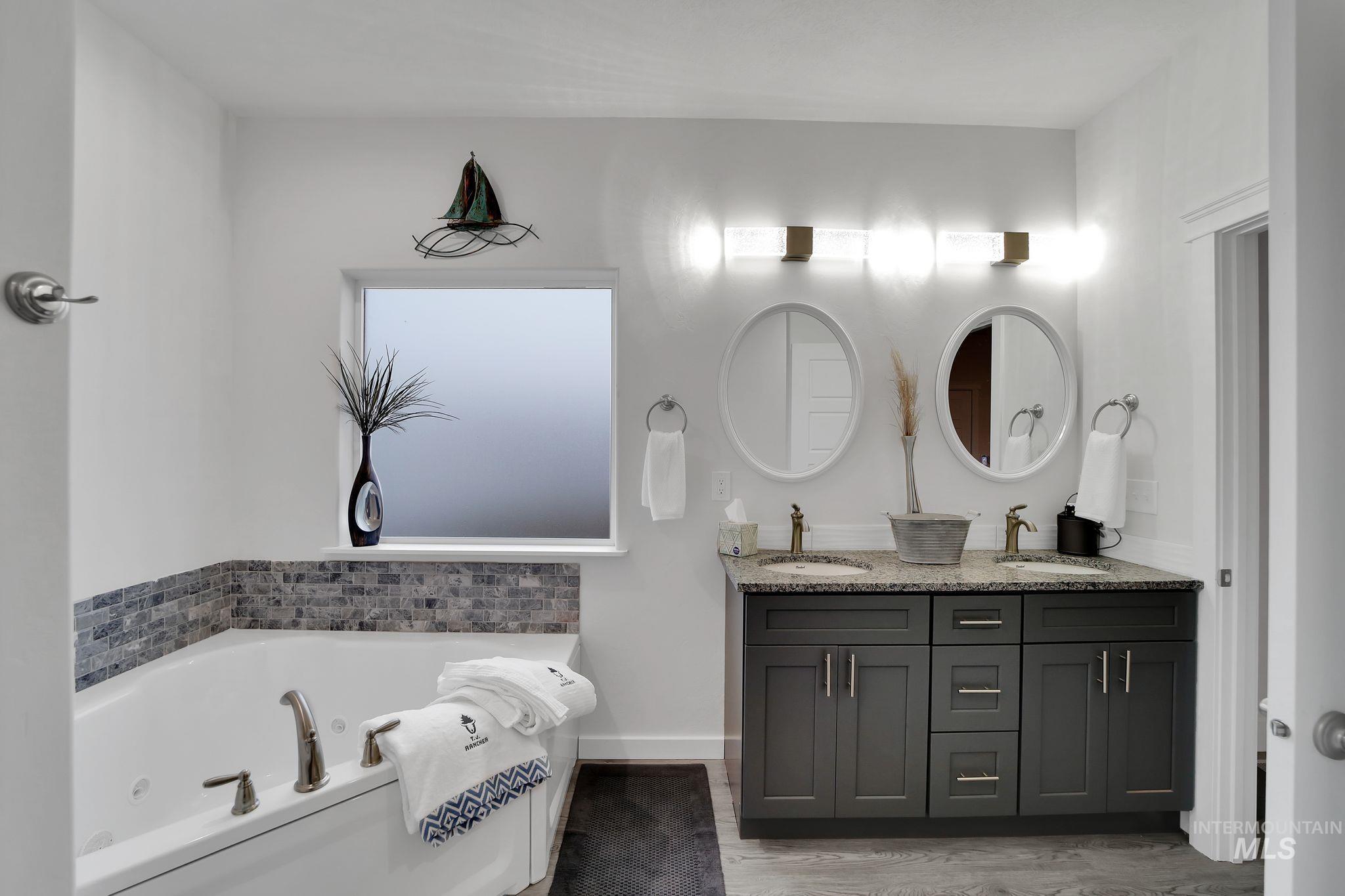1085 Easy Avenue Twin Falls, ID 83301 - Photo 9 of 22 Bathroom featuring a tub with jets, double vanity, and light wood-type flooring