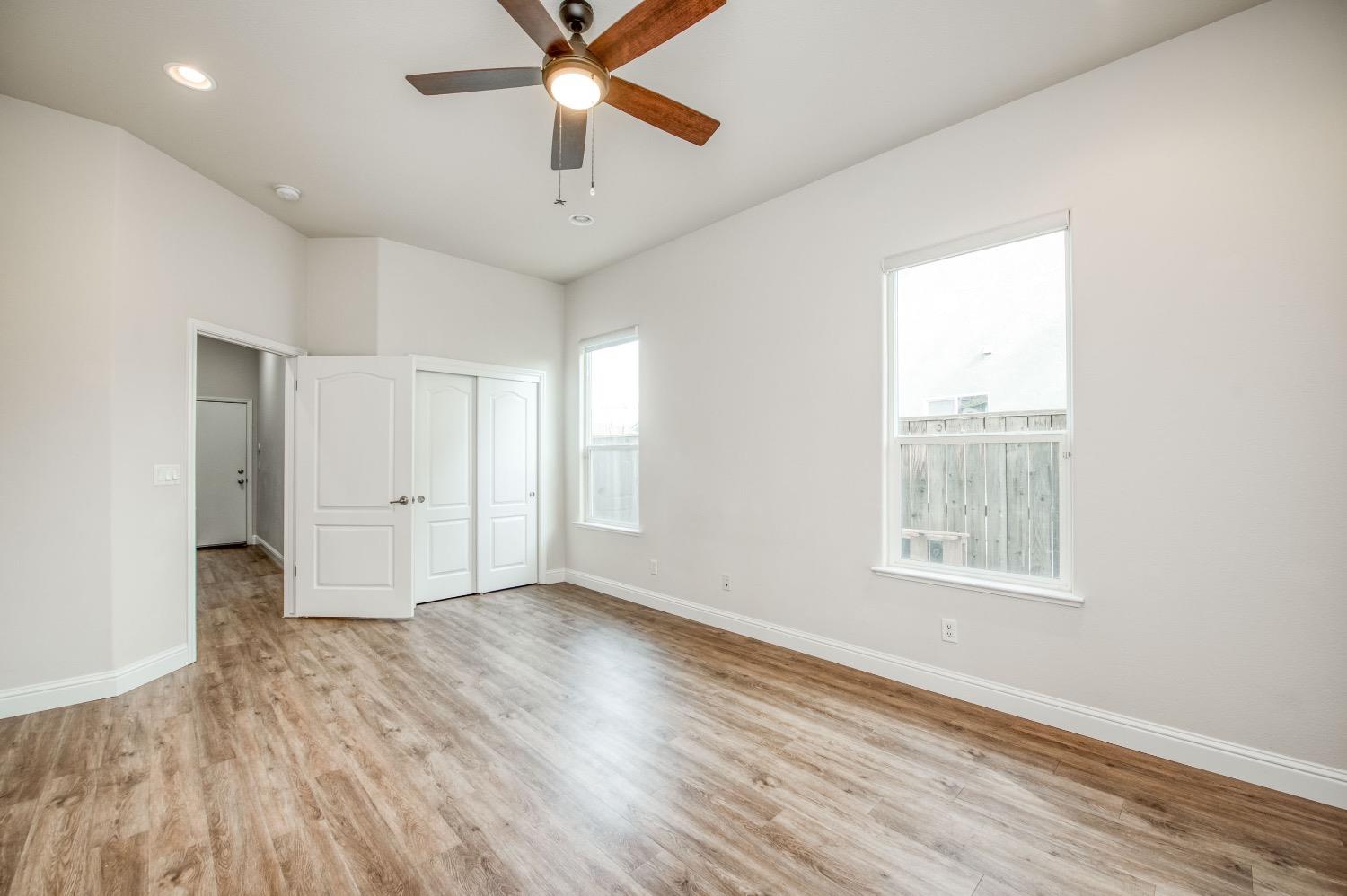 3252 Everglade Avenue Clovis, CA 93619 - Photo 17 of 31 an empty room with wooden floor chandelier fan and windows