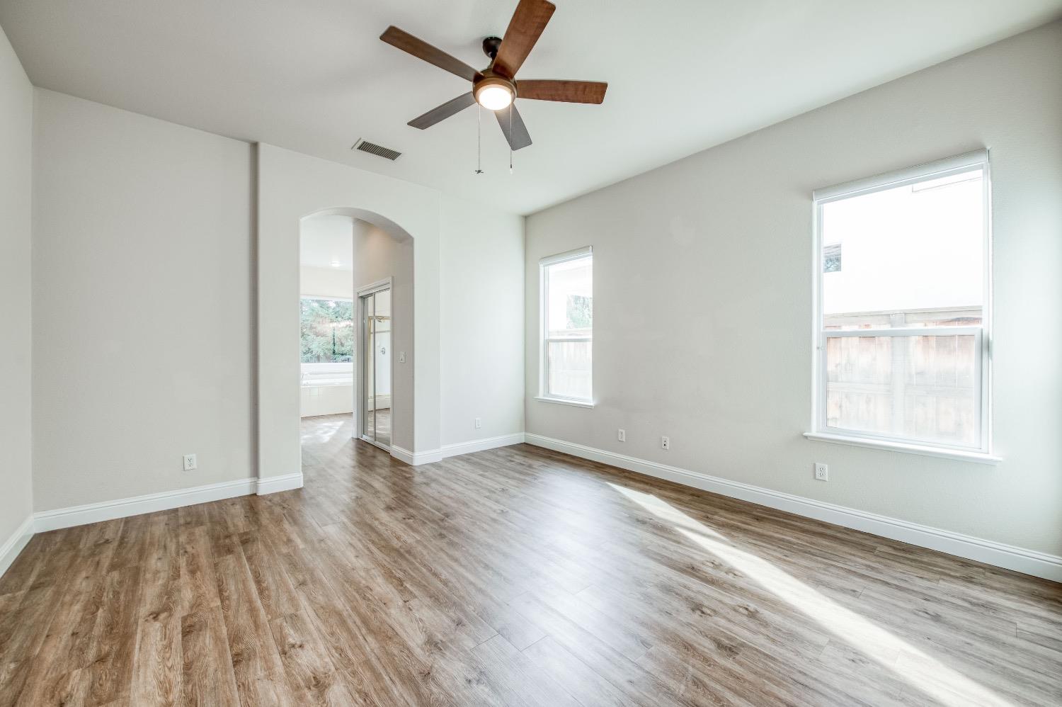 3252 Everglade Avenue Clovis, CA 93619 - Photo 25 of 31 an empty room with wooden floor a ceiling fan and windows
