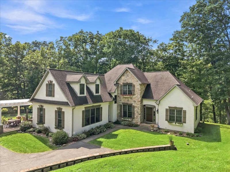 Mature trees frame a charming multi-level residence with stucco and stone veneer exterior detailing.